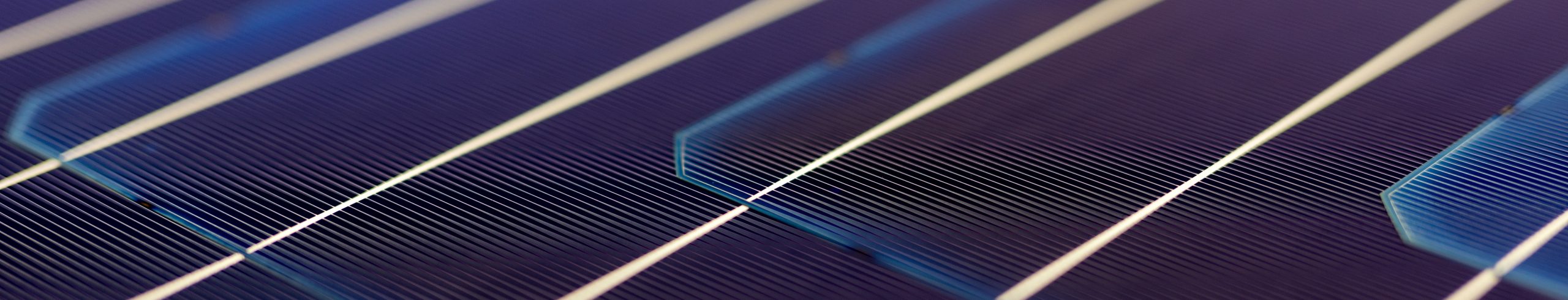 Overhead flat-lay photograph of solar panel cells showing reflective blue grid lines and a calm, technological texture.