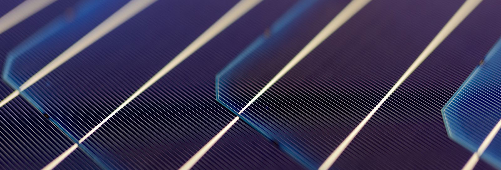 Overhead flat-lay macro photograph of a solar cell surface with textured grid lines in deep blue and purple tones.