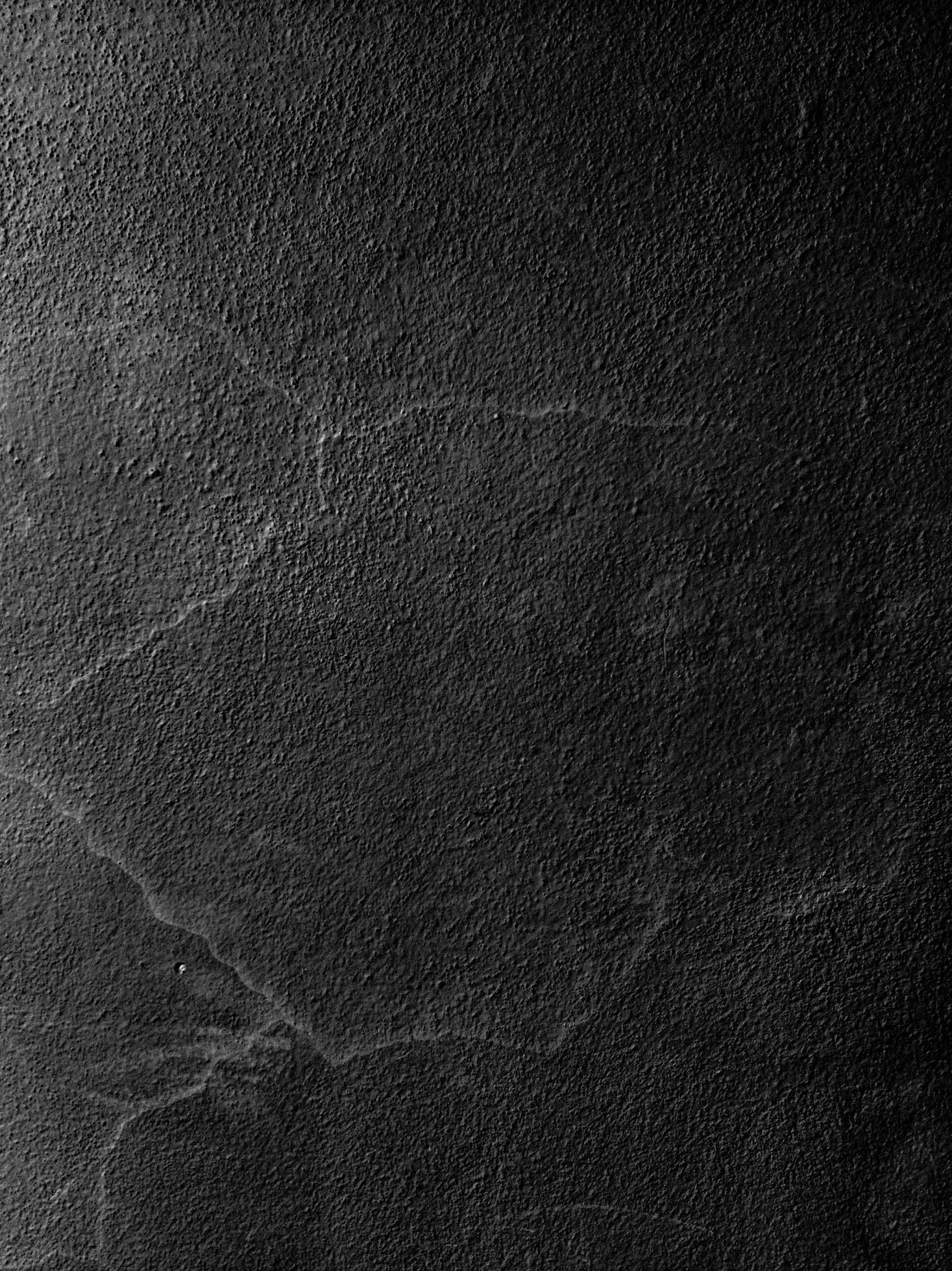 Overhead flat-lay photograph of a textured dark gray concrete surface with subtle cracks, moody and abstract.